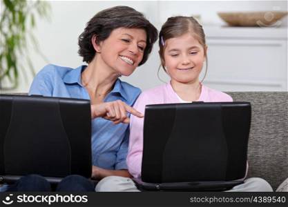 A mother and her daughter on their laptops.