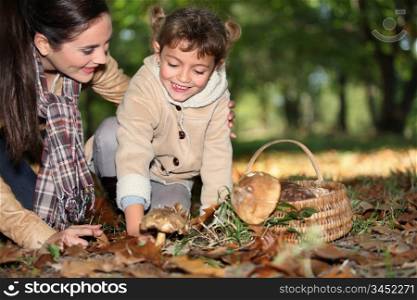 a mother and her little girl picking mushrooms in the forest