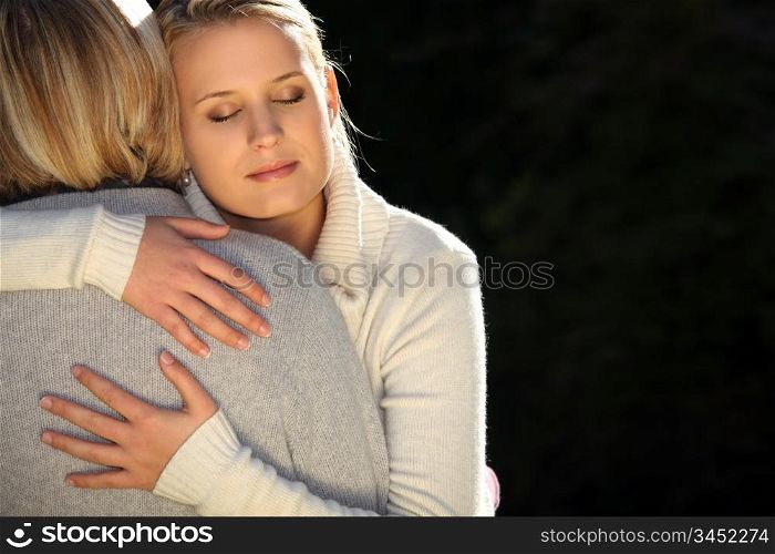 A mother and her teenage daughter hugging.