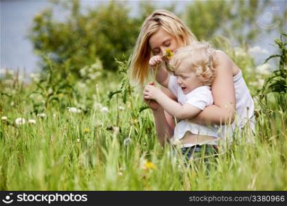 A mother and son having fun playing with flowers in a grass field