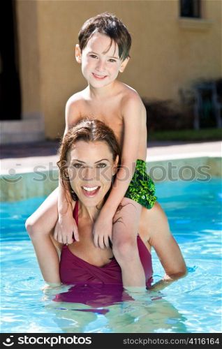 A mother having fun with her son on her shoulders in a swimming pool