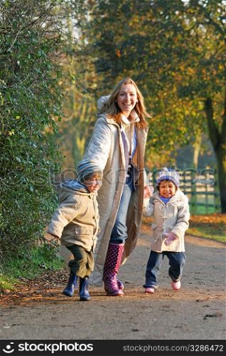 A mother, her son and daughter walking through a park filled with autumnal colors