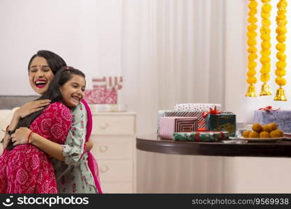 A mother hugging her daughter amidst presents,sweets and festive flower garland decoration.