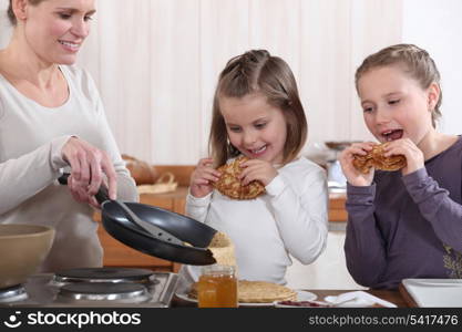 A mother making crepes for her daughters.