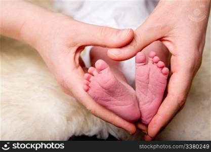 A mother&rsquo;s hands in the shape of a heart around a newborn baby&rsquo;s feet