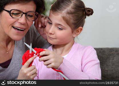A mother teaching her daughter how to knit.