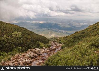 A mountain stream in the high Tatras and a valley in the distance at the foot of the mountains