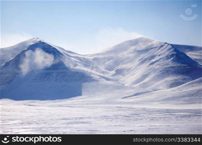 A mountain with blowing snow in a winter landscape