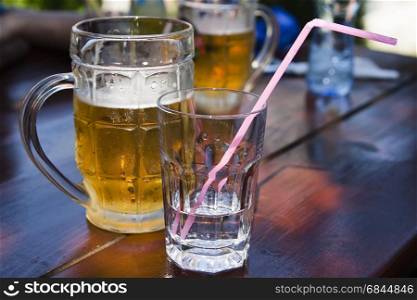 A mug of beer and a glass of water standing on a table in a cafe