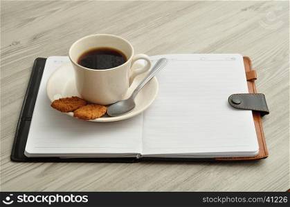 A mug of coffee, biscuits and a notebook