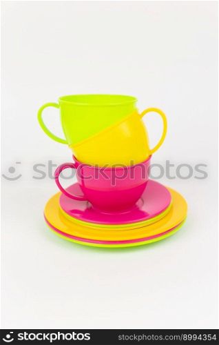 a multi-colored plastic cups and plates on a white background kitchen set. multi-colored plastic cups and plates on a white background kitchen set