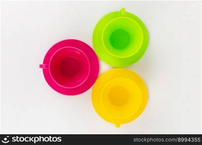 a multi-colored plastic cups and plates on a white background kitchen set. multi-colored plastic cups and plates on a white background kitchen set