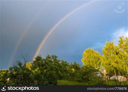 A multicolor rainbow against a dark cloudy sky on a summer day, Russia.