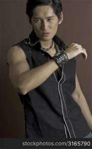 A muscular asian male model in a black waistcoat and a studded bracelet