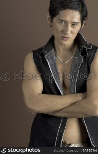 A muscular asian male model in a black waistcoat on brown background