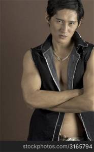 A muscular asian male model in a black waistcoat on brown background