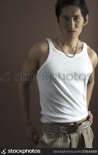 A muscular asian male model in a white vest over a brown background