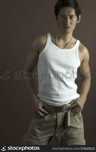 A muscular asian model in a white singlet and cargo pants