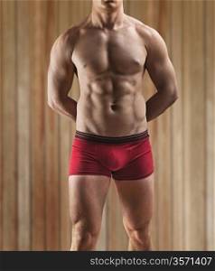 a muscular male torso on a background of the wooden wall