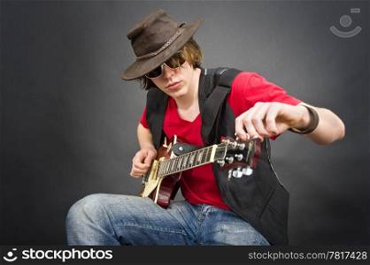 A musician wearing an old leather hat tuning his guitar