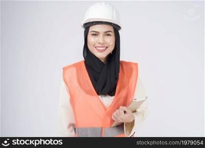 A muslim woman engineer wearinng a protective helmet over white backgroud studio