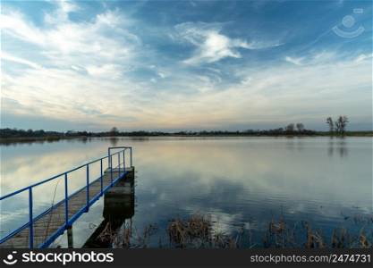 A narrow jetty on a calm lake and clouds, Staw, Poland