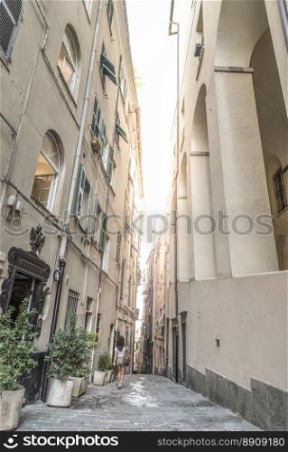 A narrow street between high buildings, near to Piazza de Ferrari, in the old center of Genoa, Italy.