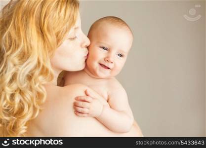 A natural blonde caucasian mother kissing happy baby