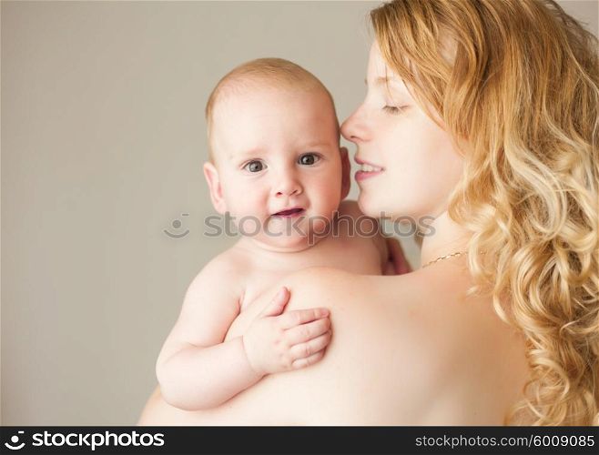 A natural blonde caucasian mother kissing happy baby. Mother and baby