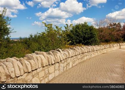 A natural old stone wall on a sidewalk in a park in Hamilton&#xA;Canada in the summer.&#xA;