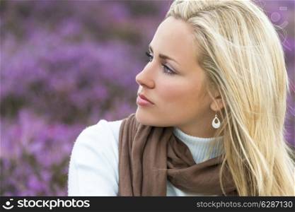 A naturally beautiful young blond woman in a field of purple heather flowers