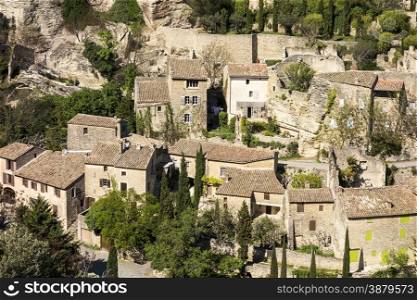 A neighborhood section of the old part of Gordes, a picturesque village in the Luberon area of France, sits below a range of rocky cliffs.
