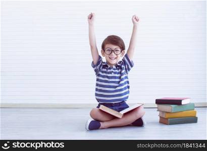A nerd caucasian little boy is happy after finishing reading books