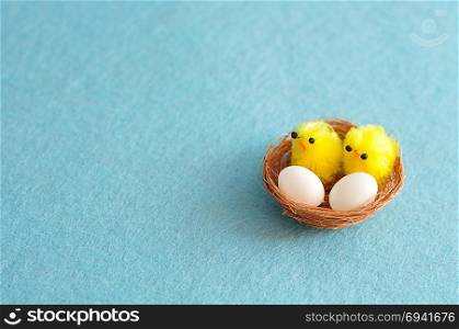 A nest with two eggs and two baby chicks on a blue background