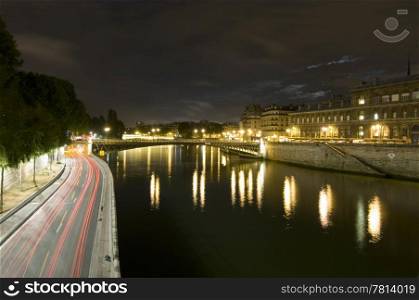 A nightly view over the Seine with it&rsquo;s many bridges, and ring road, close to Ile de la Cite. The moon shines through a break in the clouds