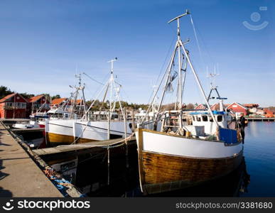 A number of fishing boats sit at dock on a warm summer day.