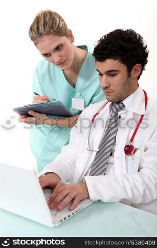A nurse and a doctor checking their laptop.