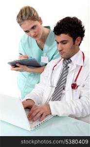 A nurse and a doctor checking their laptop.