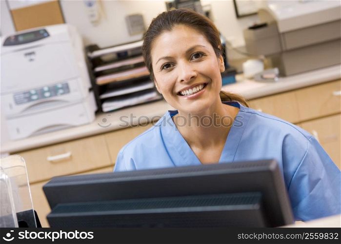A Nurse Sitting At A Computer At The Reception Area Of A Hospital