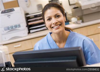 A Nurse Sitting At A Computer At The Reception Area Of A Hospital