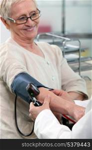 a nurse taking blood pressure of a smiling senior woman