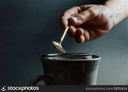 A old hand preparing a tea over a dark background with copy space and dark tones