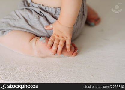 A one-year-old baby is sitting on the floor.. The babys tiny arms and legs 4239.