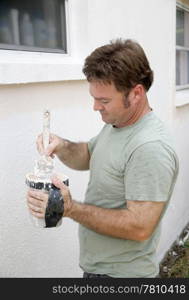 A painter dipping his brush in a paint cup and preparing to edge around a window.