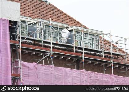 A painter working on a covered scaffolding