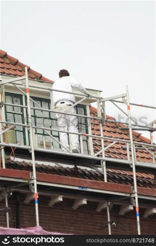 A painter working on a roof high scaffold