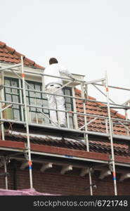 A painter working on a roof high scaffold
