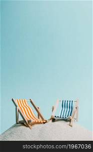 A pair of beach chair over the sand with a pastel blue background, copy space summer relax concept