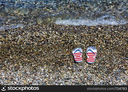 A pair of beach color slippers by the sea