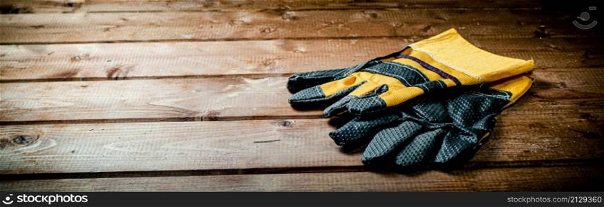 A pair of construction gloves on the table. On a wooden background. High quality photo. A pair of construction gloves on the table.